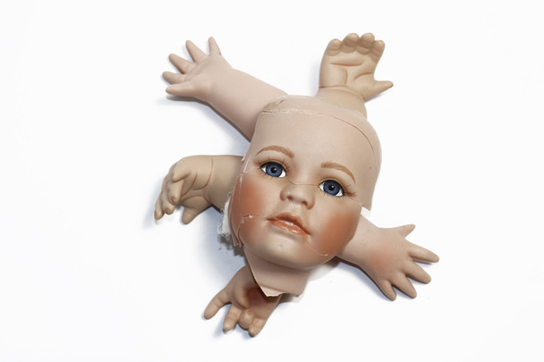 Cabeça de boneca quebrada e partes do corpo no fundo branco
 - Foto, Imagem