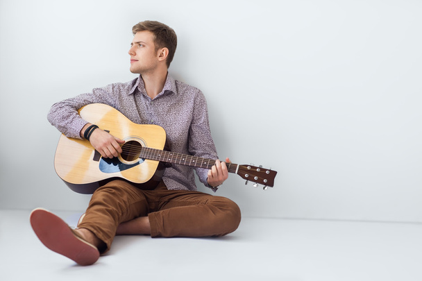 Man playing guitar sitting on floor  - Фото, зображення