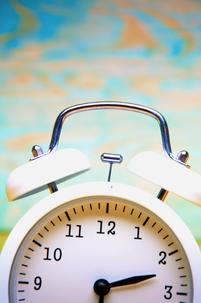 Reloj despertador blanco aislado sobre fondo de madera colorido
 - Foto, imagen