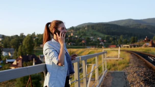 Smiling beautiful young woman with smartphone in mountains - Záběry, video
