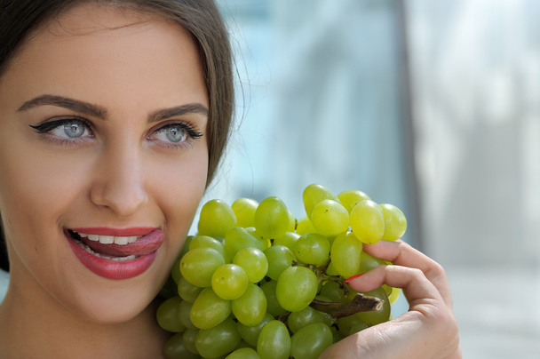 Woman posing with a bunch of grapes and smiling. - Фото, изображение