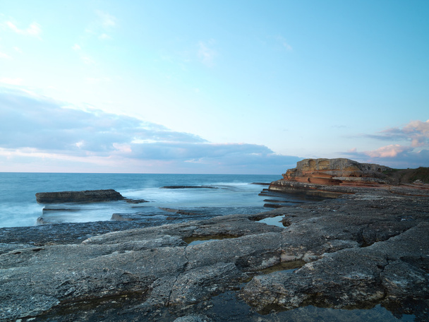 lange belichtingstijd shot op rotsen met golven van de zee - Foto, afbeelding
