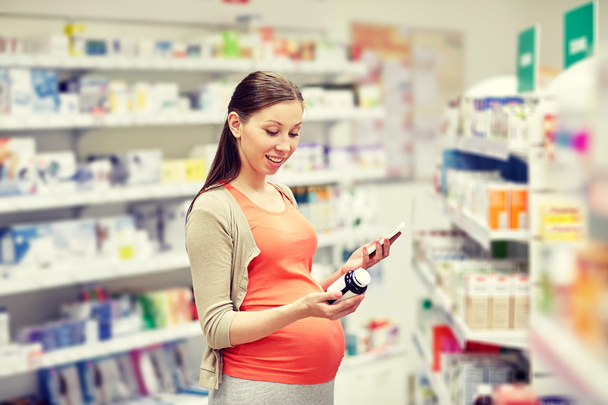 mulher grávida feliz com smartphone na farmácia
 - Foto, Imagem