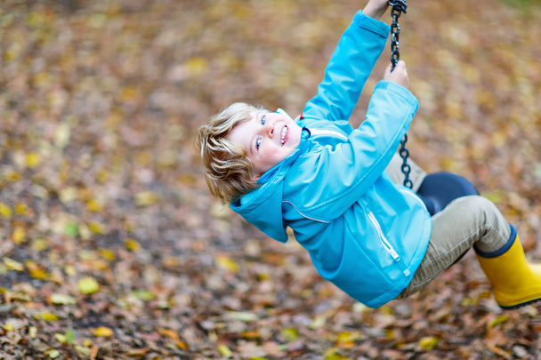 Μικρό παιδί αγόρι, διασκεδάζοντας σε φθινόπωρο παιδική χαρά - Φωτογραφία, εικόνα