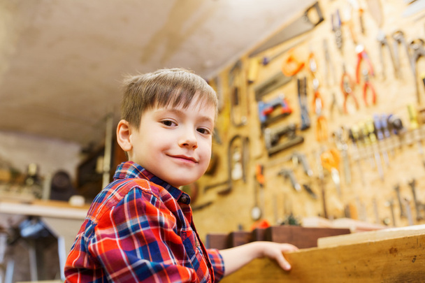 happy little boy with wood plank at workshop - Foto, afbeelding