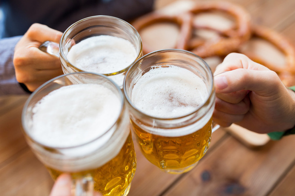 close up of hands with beer mugs at bar or pub - Fotografie, Obrázek