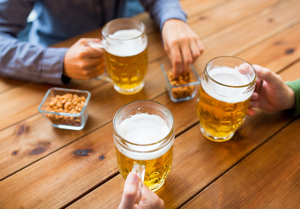 close up of hands with beer mugs at bar or pub - 写真・画像