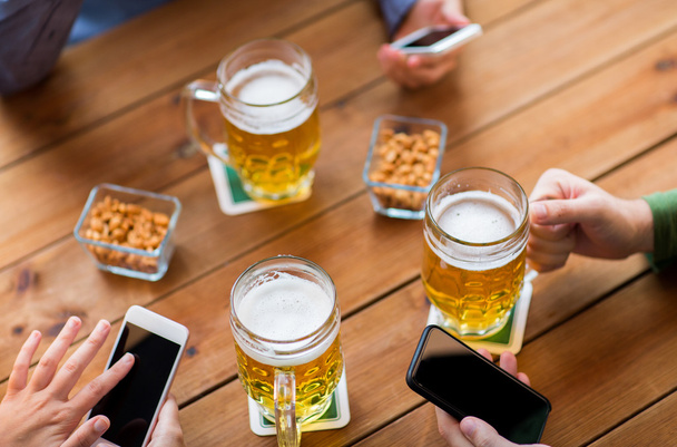 close up of hands with smartphones and beer at bar - Foto, imagen