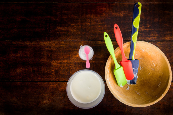 Цветные хлебобулочные весла на деревянной чаше на темном деревянном столе. приготовление пищи для приготовления крема
. - Фото, изображение