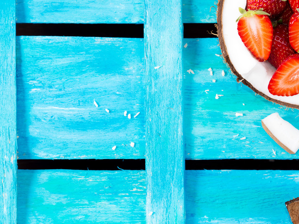 Bright blue background with coconut and strawberries - Photo, Image
