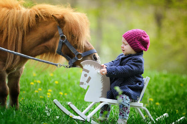 Petite fille sur cheval à bascule en bois et poney
 - Photo, image