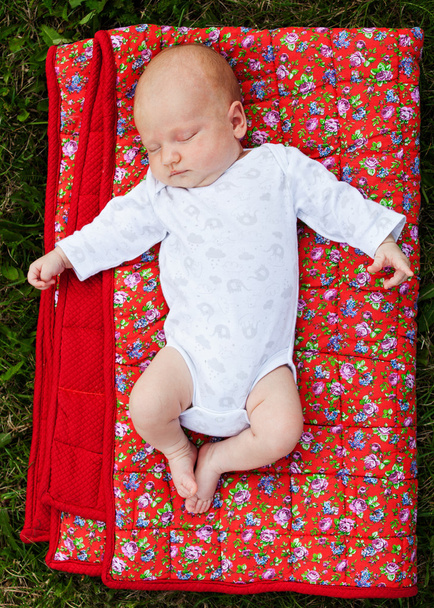 Newborn baby laying on a red blanket - Foto, immagini