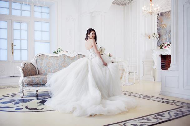 Portrait of beautiful laughing bride. Wedding dress with open back. Luxurious light interior - Zdjęcie, obraz