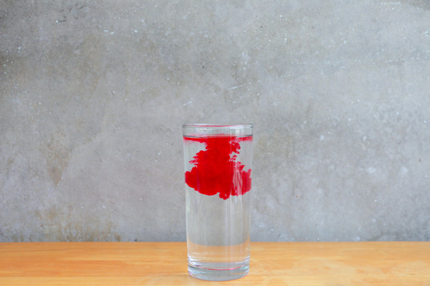 Efeito da gota de água e vidro de água sobre a mesa de madeira na frente do fundo da parede de cimento
  - Foto, Imagem