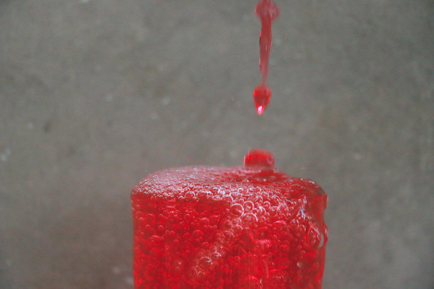 Pudotusveden ja vesilasin vaikutus sementtiseinän taustan edessä olevaan puupöytään
  - Valokuva, kuva