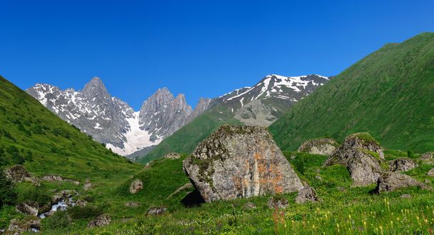 Paisaje de verano con grandes piedras y nieve de montaña
. - Foto, Imagen