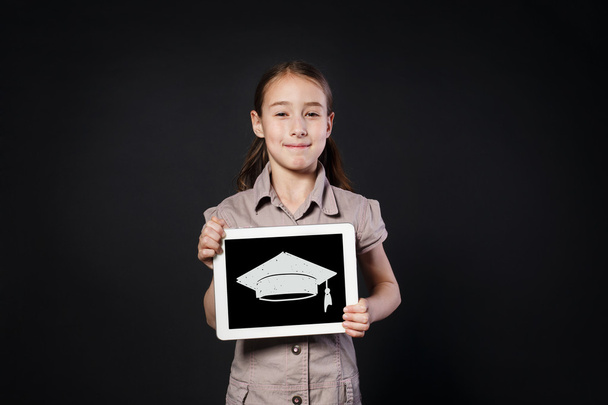 Ευτυχισμένος κορίτσι δείχνει οθόνη ψηφιακή δισκίο με καπάκι αποφοίτηση - Φωτογραφία, εικόνα