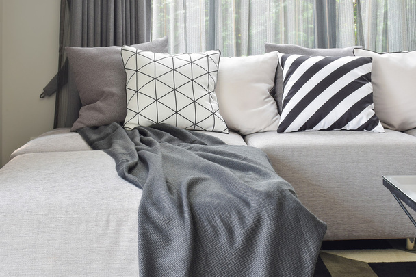 Light gray L shape sofa with varies pattern and white pillows in modern living corner - Foto, Imagem