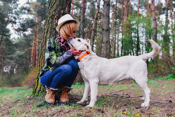 Chica joven con un perro en el bosque
 - Foto, imagen