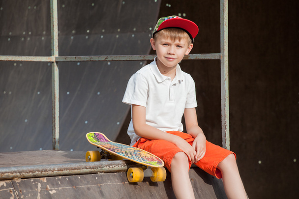 Boy in a cap sits with the Board and looks with a smile - 写真・画像