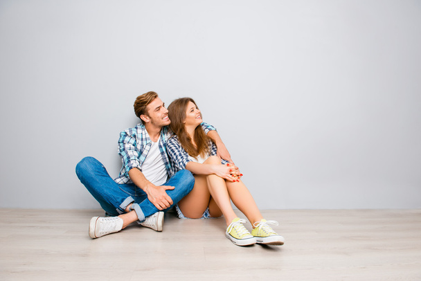 Excited man and woman sitting on floor and looking on smth - Foto, Imagen