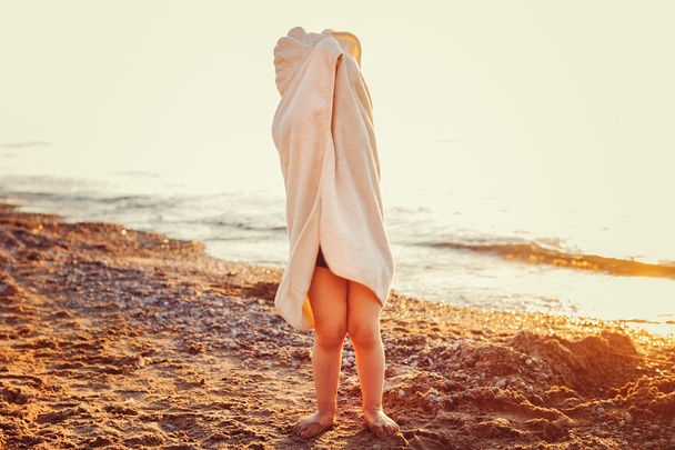 Portrait of cute adorable happy toddler little girl boy with beach towel hiding covering having fun, lifestyle sunset summer mood, toned with Instagram filters - Photo, Image