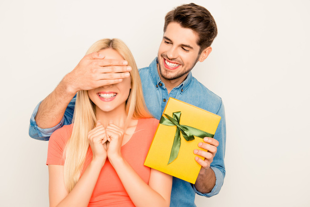 Happy man closing eyes of his wife and holding present - Фото, зображення