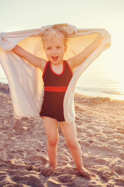 Portret van leuk schattig gelukkig lachend peuter meisje met handdoek op strand maken poses gezichten hebben fun, emotionele gezicht expressie, levensstijl zonsondergang zomer stemming, afgezwakt - Foto, afbeelding