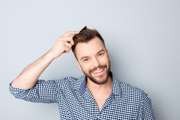 Portrait of happy smiling handsome guy combing his hair - Fotografie, Obrázek
