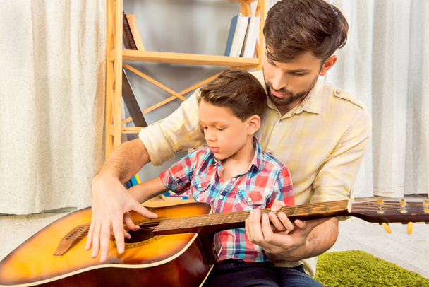 Young father teaching his little son to play on guitar - Fotoğraf, Görsel