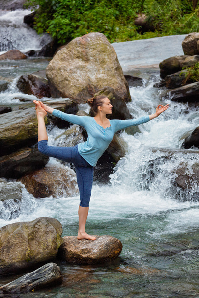 Woman doing yoga asana Natarajasana outdoors at waterfall - Photo, Image