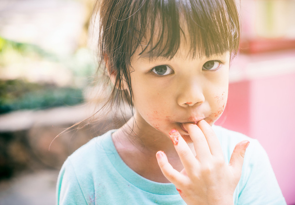 Голодный бедный азиатский ребенок лижет свою руку для последнего теста ее пищи
. - Фото, изображение