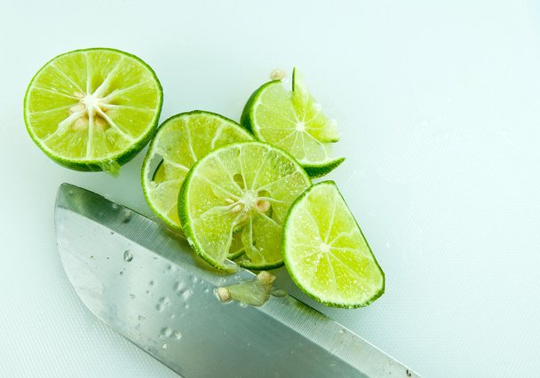 Sliced lime and knife on kitchen board - Фото, зображення