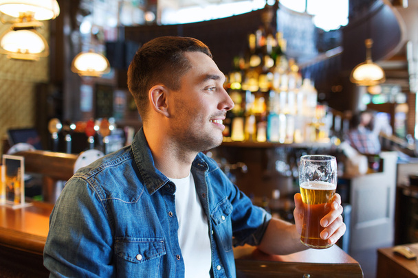 happy man drinking beer at bar or pub - 写真・画像