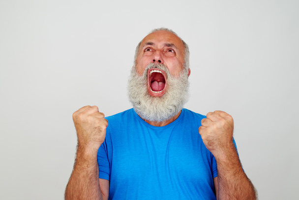 Yaşlı adam beyaz bac karşı sıkıştırılmış yumruklar ile öfke içinde çığlık - Fotoğraf, Görsel