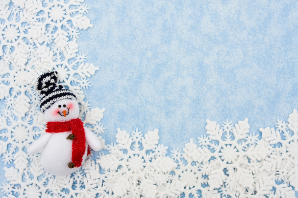 Copos de nieve con muñeco de nieve haciendo un borde sobre un fondo azul
 - Foto, imagen