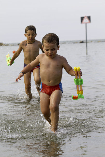 glückliche Kinder spielen mit Wasserpistole ins Meer, Urlaub in Italien - Foto, Bild
