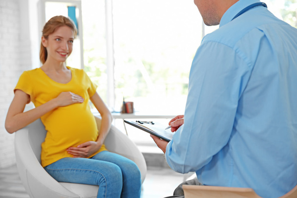Pregnant young woman visiting doctor - Фото, изображение