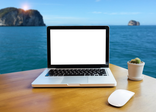 Vista frontal do laptop na mesa de escritório ao ar livre e vista para o mar fundo turva. Laptop com tela em branco e pode ser adicionado seus textos ou outros no Laptop. Conceito portátil. - Foto, Imagem