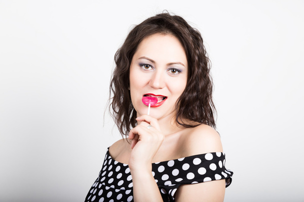 Портрет счастливой красивой молодой женщины, облизывающей сладкие конфеты и выражающей различные эмоции. симпатичная женщина с сердцеобразным лепестком
 - Фото, изображение