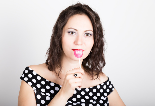 Portrait of happy beautiful young woman licking sweet candy and expressing different emotions. pretty woman with heart shaped lollipop - Foto, Imagen