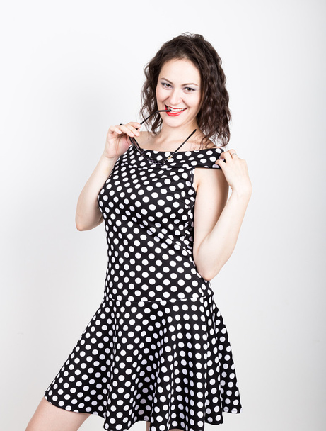 Beautiful young woman removes sun glasses, wears a dress with polka dots. expressing different emotions - Фото, зображення