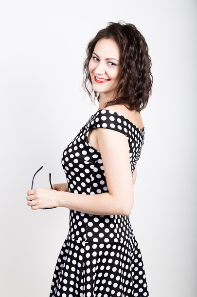 Beautiful young woman removes sun glasses, wears a dress with polka dots. expressing different emotions - Foto, afbeelding