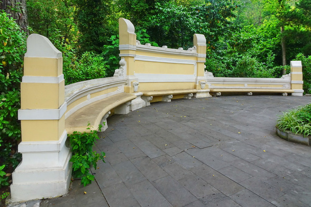 antike gelbe Steinbank im öffentlichen botanischen Park und tropischer Sommergarten im Hintergrund, Russland, Sotschi - Foto, Bild