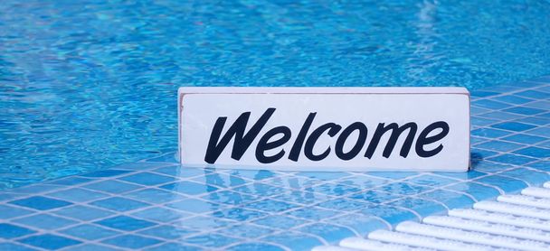 Welkom teken op wit bord In zwembad wateroppervlakte - Foto, afbeelding
