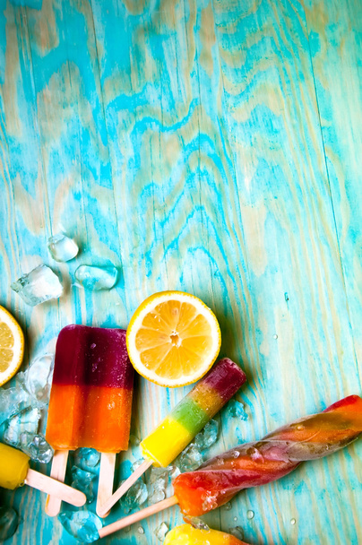 Colorido lolly hielo y friuts sobre fondo de madera azul
 - Foto, Imagen