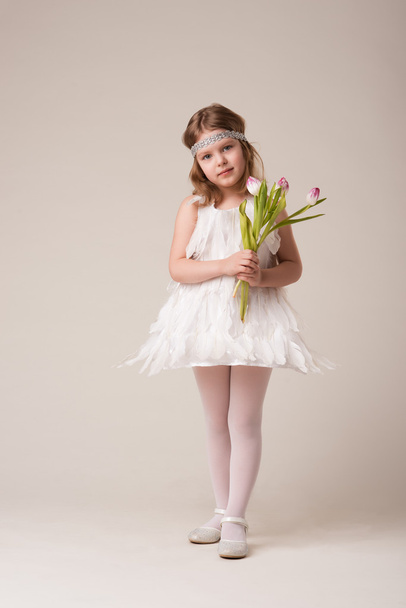 Ritratto di una bella ragazza allegra in un vestito di piume bianche, con fiori in mano
 - Foto, immagini