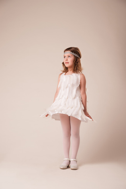  Portrait of a beautiful cheerful girl in a dress of white feathers - Photo, image