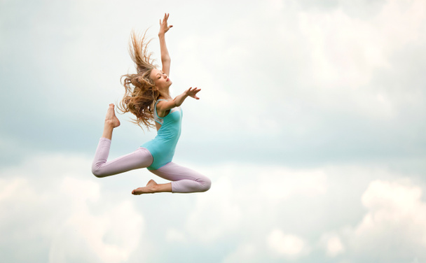 Красива молода блондинка в синій Gimnastic купальника стрибки  - Фото, зображення