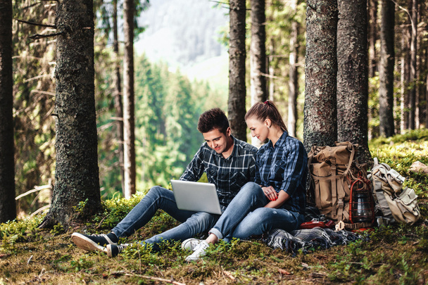 Kilka turystów, siedząc sobie i przeglądając laptopa w lesie. Koncepcja aktywnego wypoczynku - Zdjęcie, obraz